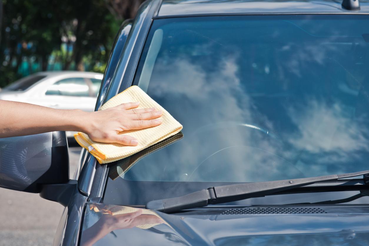 Someone is wiping their car's windshield with a microfiber cloth