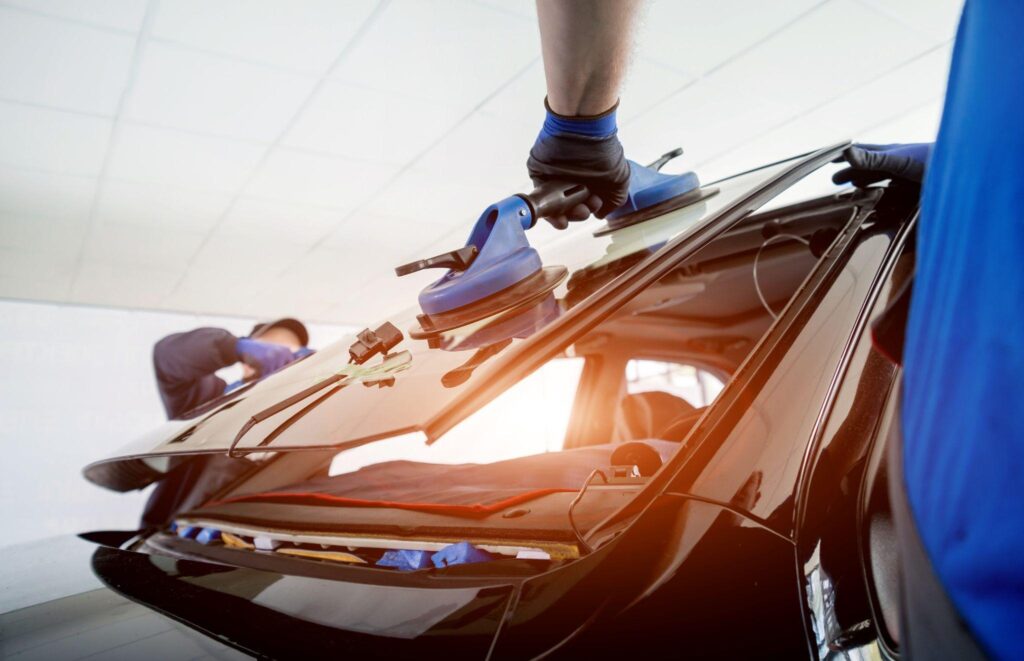 Technicians putting on a new front windshield.